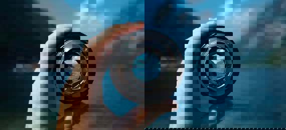 A hand holding a camera lens bringing the background into focus.