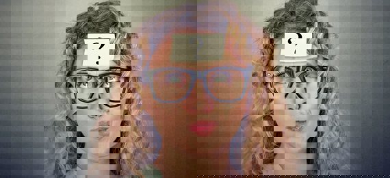 A person with a post-it on her forehead with a question mark on it. She is looking up.