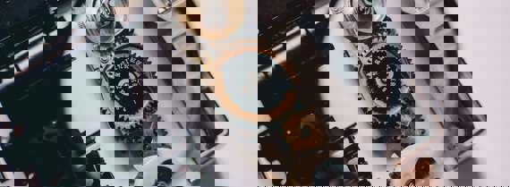 A person using magnifying glass to see gold and white device gear of a camera parts (1)