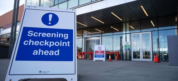 Floor-standing displays indicates "Screening Checkpoint ahead" in front of the entrance of a business building.