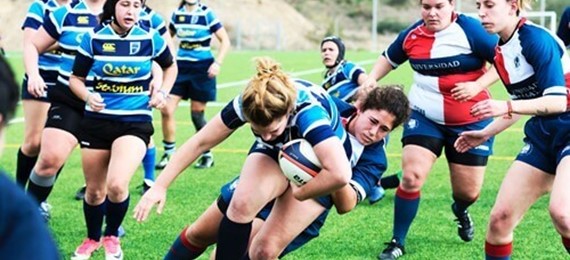 Rugby game with one of the players holding a ball and the other tackling that player from behind.