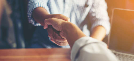 Handshake of two business people with a papers on the desk.