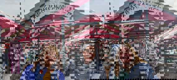Three people standing in front of town market. They are smiling into the camera.