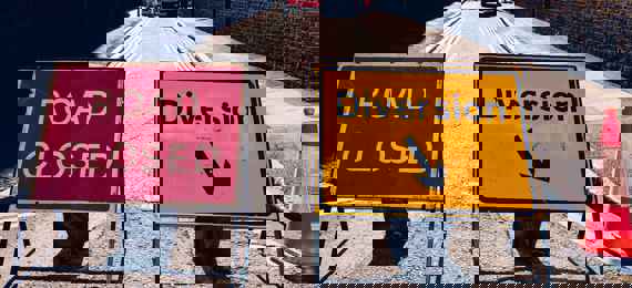 Two  signs: one red saying "road closed", one yellow saying "diversion" on a closed road.