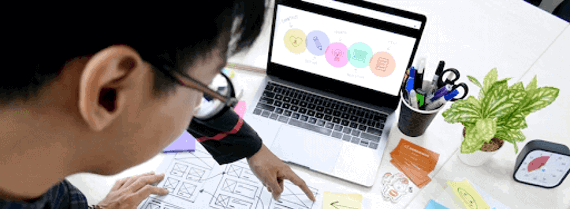 People looking down at the desk with laptop, papers and plans discussing a project