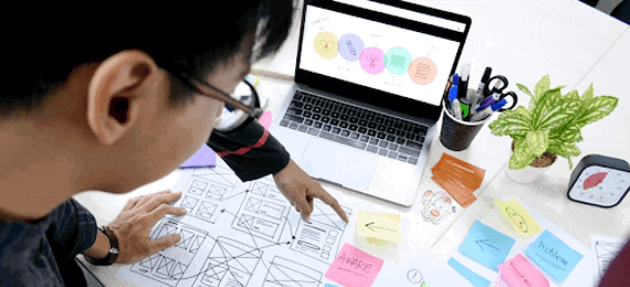 People looking down at the desk with laptop, papers and plans discussing a project.
