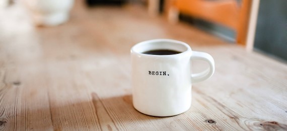 A cup of coffee on a table with the word "begin" written on it.