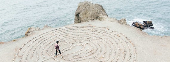 Image of person walking through a maze made of pebbles on a beach