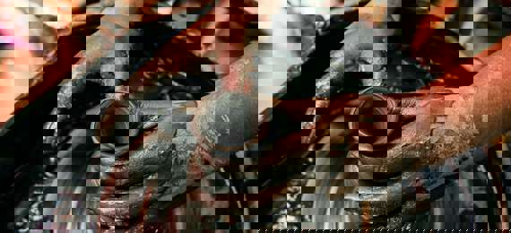 Two hands shaping a clay vase on a potter's wheel.