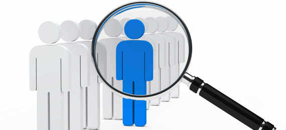 Illustration of magnifying glass pointed at a blue paper cutout of a person with white coloured cutouts lined up on one side..