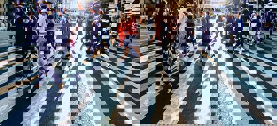 People crossing street on zebra in a city.