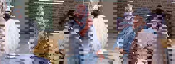 Group of people sitting in a circle. On person is talking and holding papers